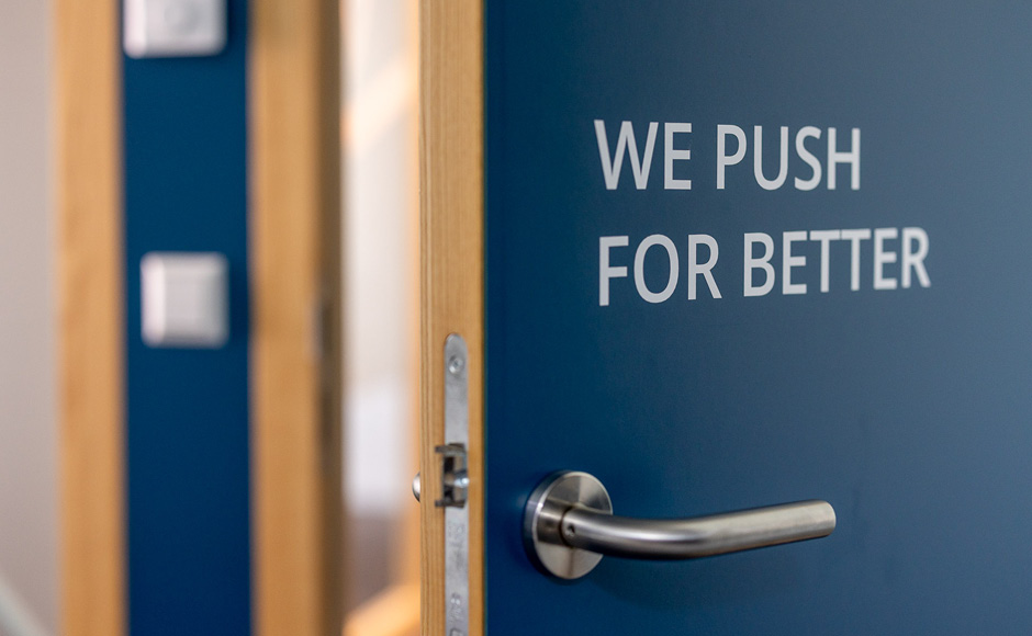 dunkelblaues Türblatt mit augenzwinkerndem Spruch: we push for better