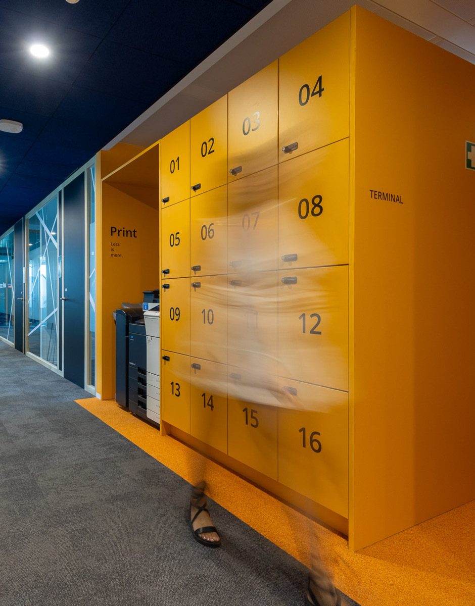 Orangefarbene Locker-Wand neben einem Druckbereich in einem offenen Office.